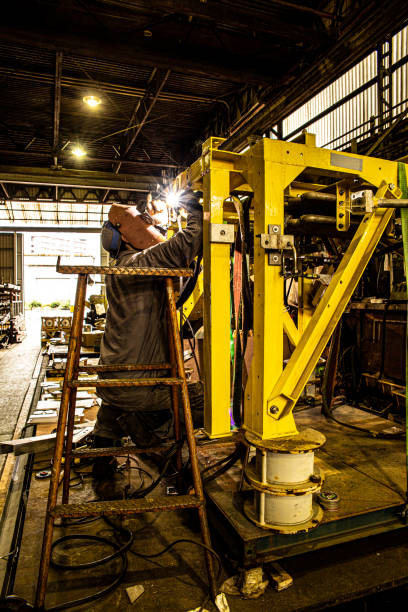 Male worker welding steel, sparks from light, protective masks and gloves increase safety