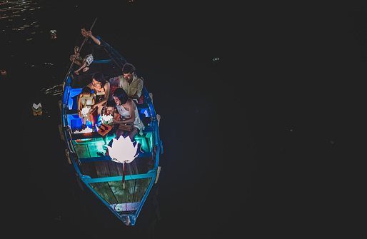 top angle view of a group of asian family on a boat making wishes and putting the lantern on the river as Vietnamese tradition at hoi an river at night