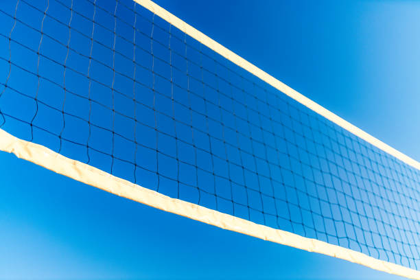 Beach volleyball net from low wide angle as photographed on a sunny day and clear blue sky with no clouds, outdoors in natural light. Image is ideal for background. Shot on Canon EOS R full frame with prime lens for highest quality results and polarising filter to emphasise colour of the sky and remove reflections.