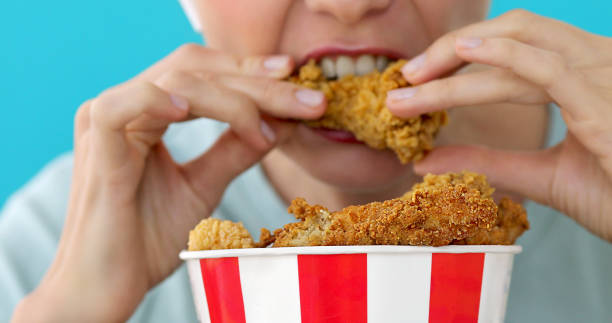 istock Girl eating chicken wings 1169695778