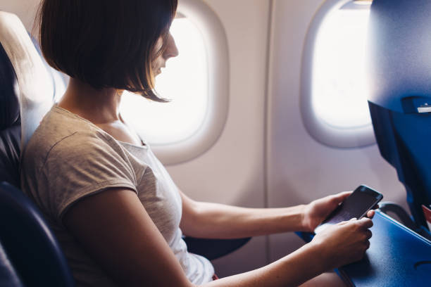 istock Young woman on a plane with a smartphone in her hands 1169698870