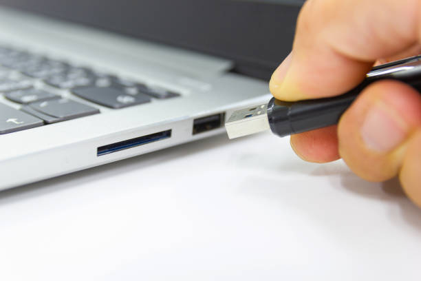 istock hand man hold Flash drive connect to USB port plug-in computer laptop 1169703536