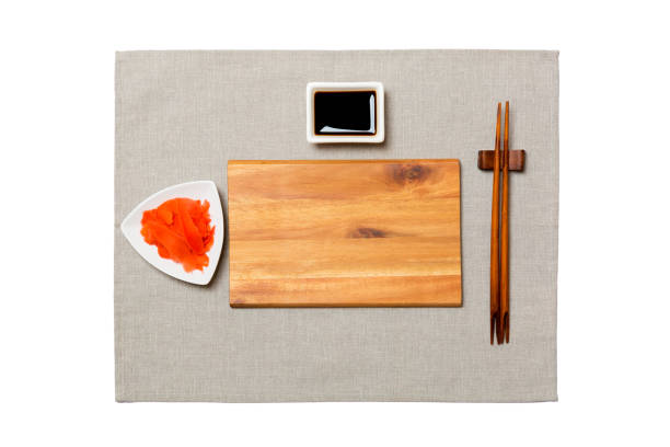 istock Empty rectangular brown wooden plate with chopsticks for sushi, ginger and soy sauce on grey napkin background. Top view with copy space for you design 1169703844