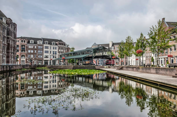 Pond, houses and market hall in postmodern style Helmond, The Netherlands, August 16, 2019: neoclassicist houses and market hall in postmodern neighbourhood Brandevoort reflect in the pond on the central square new urbanism stock pictures, royalty-free photos & images