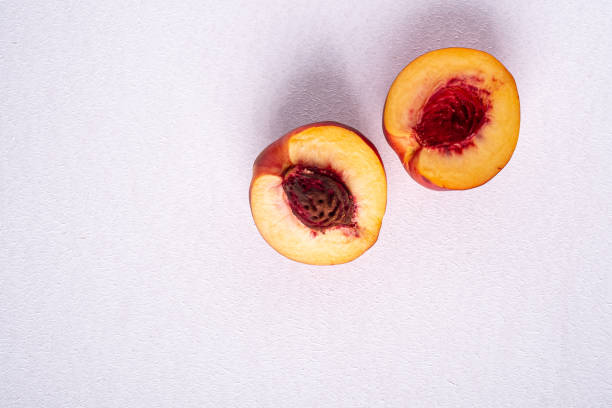 Two slice of peach nectarine fruit with seed on white background, copy space, top view, flat lay