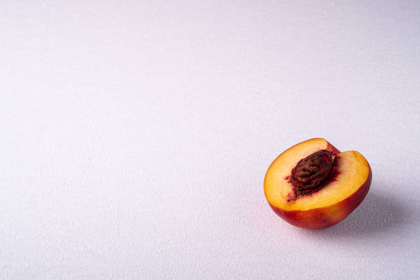 Single slice of peach nectarine fruit with seed on white background, copy space, angle view