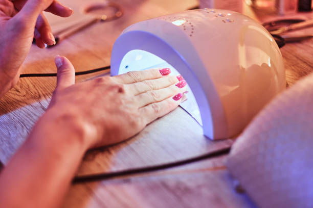 Client at manicure salon dryes gel nails in UV light