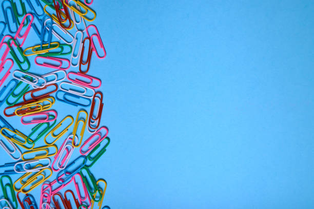 istock Colorful paper clips on blue pastel texture, copy space. Top view, flat lay. Back to school, business, education concept. Abstract background 1169712389