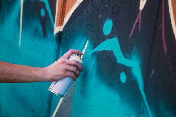 artista callejero pintando graffiti colorido en la pared genérica - concepto de arte moderno con el tipo urbano realizando y preparando murales en vivo con aerosol multicolor - profesiones del espectáculo fotografías e imágenes de stock