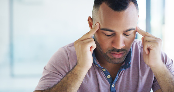 Cropped shot of a handsome young businessman sitting alone in his office and suffering from a headache