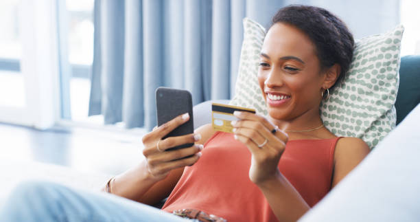 Shopping until my heart is content Cropped shot of an attractive young woman lying down on her sofa and using her cellphone for online shopping convenience photos stock pictures, royalty-free photos & images