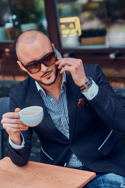 istock Serious sucessful man is calling by mobile and enjoying his coffee. 1169717458