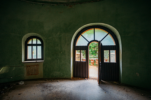Old ruined abandoned mansion interior, vaulted window and door.