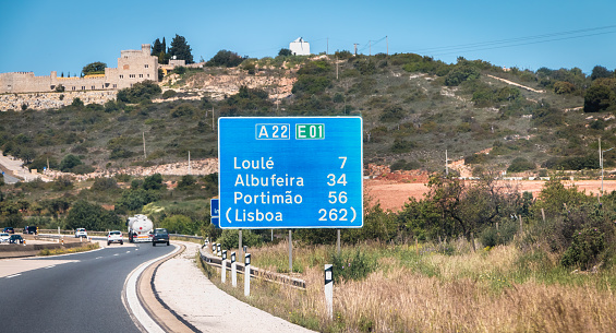Faro, Portugal - September 16, 2018: blue road sign on A22 highway indicating the direction of Lisbon, Portugal on a summer day