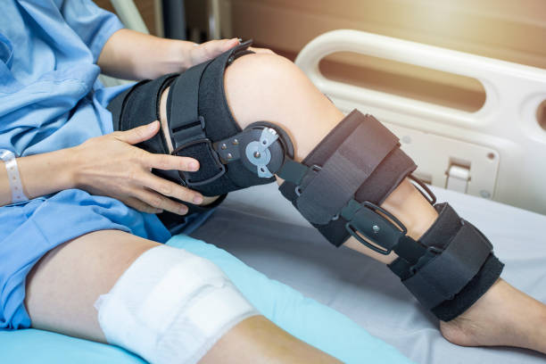 mujer asiática paciente con compresión vendaje rodillera de apoyo en la cama en hospital de enfermería.healthcare y apoyo médico. - cruciate ligament fotografías e imágenes de stock