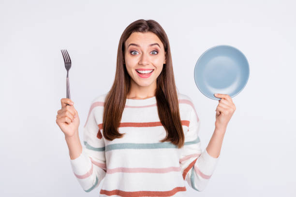 istock Hungry lady holding spoon and empty plate ready for dinner wear striped pullover isolated white background 1169725797
