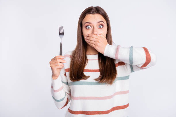 Crazy lady hiding mouth with arm remind herself about taboo on night eating wear striped pullover isolated white background Crazy lady hiding mouth with arm remind herself about taboo on night eating, wear striped pullover isolated white background behavior femininity outdoors horizontal stock pictures, royalty-free photos & images