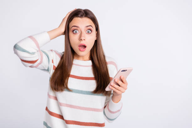 istock Confused lady with open mouth and telephone in hands wear striped pullover isolated white background 1169725997