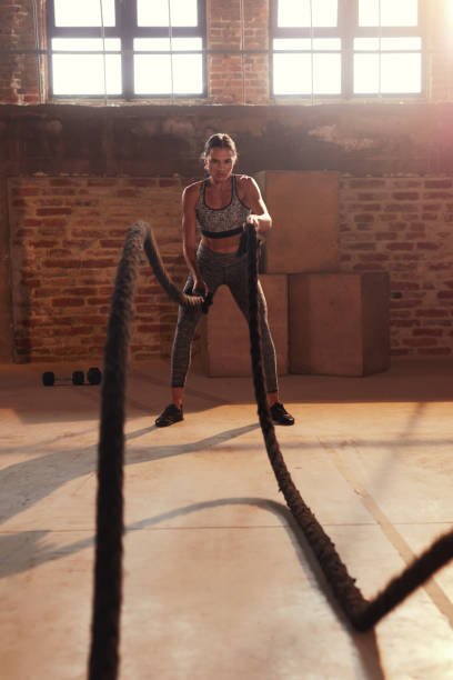 istock Rope workout. Sport woman doing battle ropes exercise at gym 1169727578
