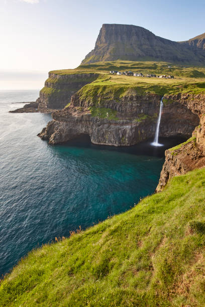 Waterfall and cliffs on Vagar. Faroe Islands coastline. Gasaladur stock photo