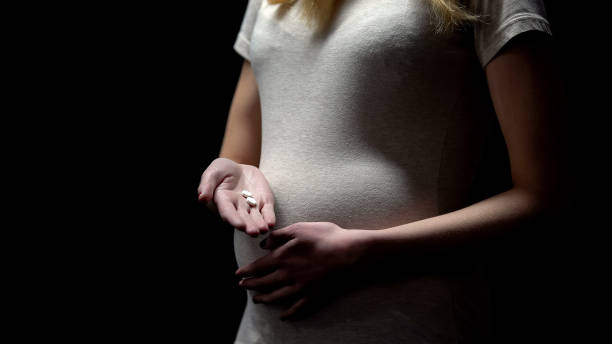 giovane donna incinta in possesso di pillole isolate su sfondo nero, tossicodipendenza - women dependency business time foto e immagini stock