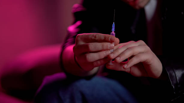 Junky holding syringe, preparing to make injection, drug abuse problem concept stock photo