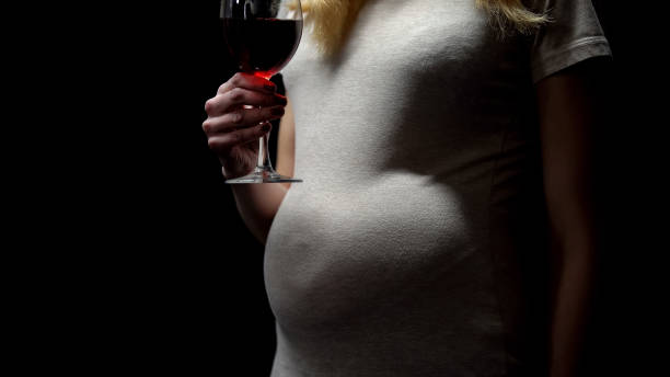 donna incinta che tiene un bicchiere di vino, dipendenza da alcol, abitudine malsana - abdomen addiction adult alcohol foto e immagini stock
