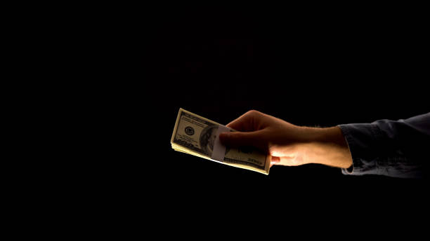 istock Male hand giving dollars, isolated on black background, bribery and corruption 1169729092
