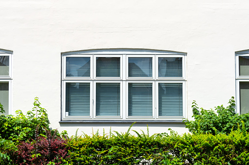 Beautiful wooden window with blinds on a white wall. Architecture. Details