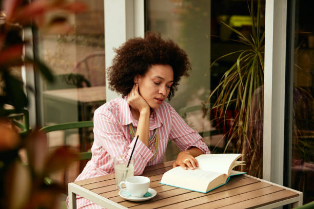 istock Woman reading book in bar. 1169734937