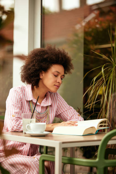 istock Woman reading book in bar. 1169735372