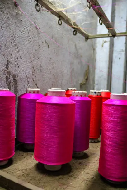 Colorful pink spools of thread for a loom await use, Varanasi, India