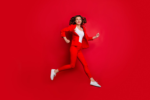Full length photo of cheerful, girl running having bright lips stick isolated over red background