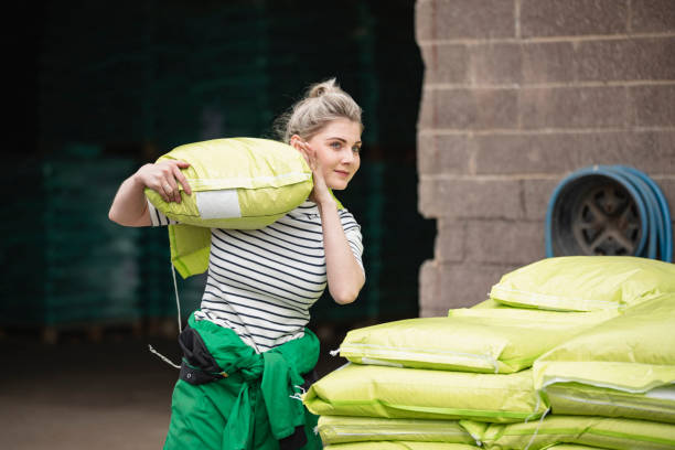 Farm Life A front-view shot of a young caucasian female farmer, she is carrying a large sack over her shoulder. northeastern england photos stock pictures, royalty-free photos & images