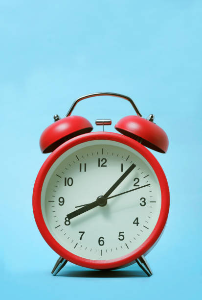 istock Red alarm clock on light blue background 1169741052