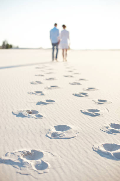 szczęśliwa para chodząca trzymając się za ręce na plaży. - men footprint beach sunset zdjęcia i obrazy z banku zdjęć