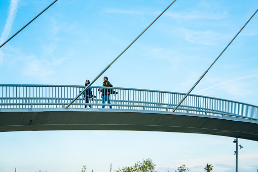 Two skaters with their longboards walking on an elevated walkway