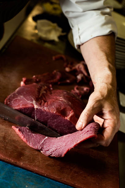 istock man cutting a piece of beef in a professional kitchen 1169744828