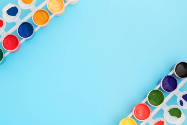 Multi-colored paint in cans on blue background. Palette of colors. Concept - creativity and school theme.