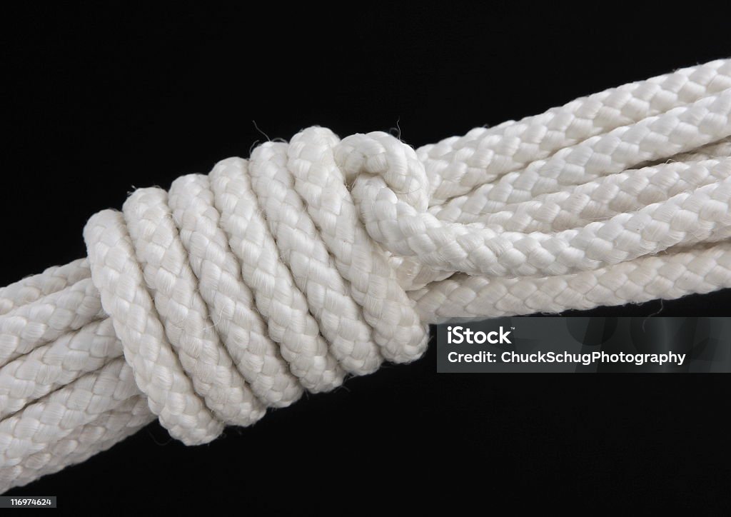 Mountain Coil Rope Knot A mountain coil rope knot used to secure climbing rope during transport to prevent tangling.  The mountaineer's coil (also alpine coil, climber's coil, lap coil, or standing coil) is a traditional method used by climbers to store and transport a climbing rope without tangling. Black Background Stock Photo