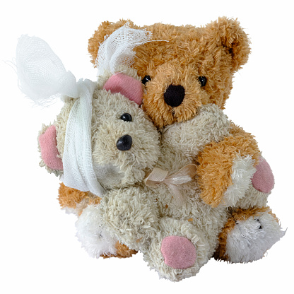 Brown male teddy bear loving and taking care of an old worn out and broken, injured smaller female bear, isolated on white. Concept image relating to love, compassion, help, concern, charity, care, etc.