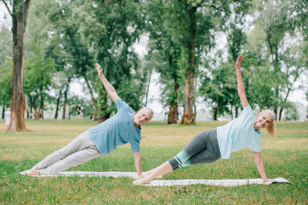 istock mature man and woman doing side plank exercise while practicing yoga on lawn in park 1169746803