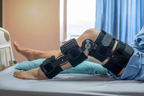 Asian woman patient with bandage compression knee brace support injury on the bed in nursing hospital.healthcare and medical support. Asian woman patient with bandage compression knee brace support injury on the bed in nursing hospital.healthcare and medical support. posterior cruciate ligament stock pictures, royalty-free photos & images