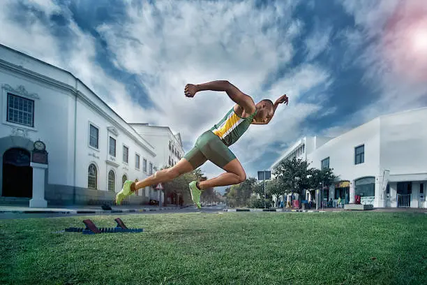 An African young male sprinter athlete froze in mid-air starting from starting blocks in the town centre of Stellenbosch South Africa