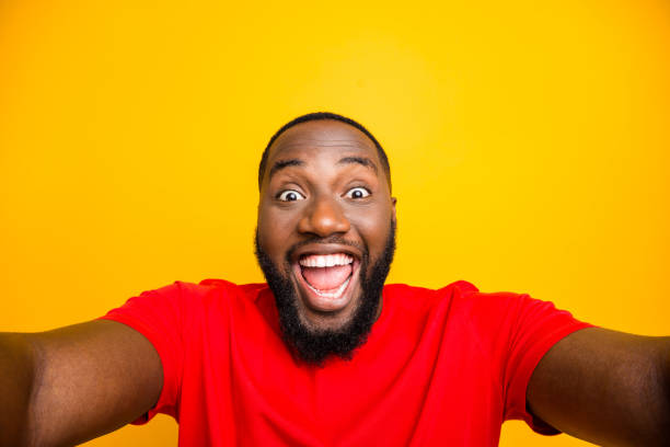 istock Self portrait of rejoicing overjoyed black man playing new camera with face delighted while isolated with yellow background 1169766505