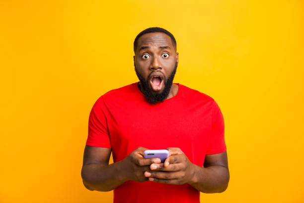 istock Photo of horrified scared surprised negative man who saw something terrible while browsing through his phone while isolated with yellow background 1169767098