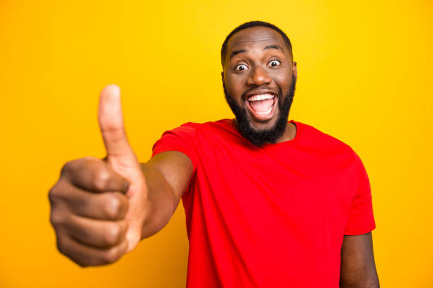 istock Photo of excited rejoicing overjoyed man delighted with something her has received while isolated with yellow background showing you like sign 1169767165