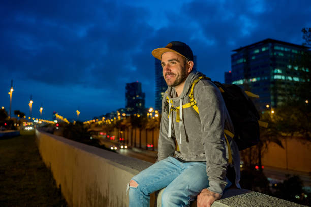 istock Cool man sitting on a wall with Barcelona at background 1169770514