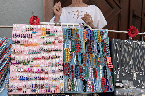 Woman Street Vendor Selling Handmade Jewelry On A Street Stand
