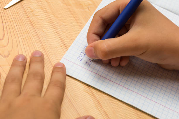istock a girl writes multiplication examples in a notebook in a cell 1169772889